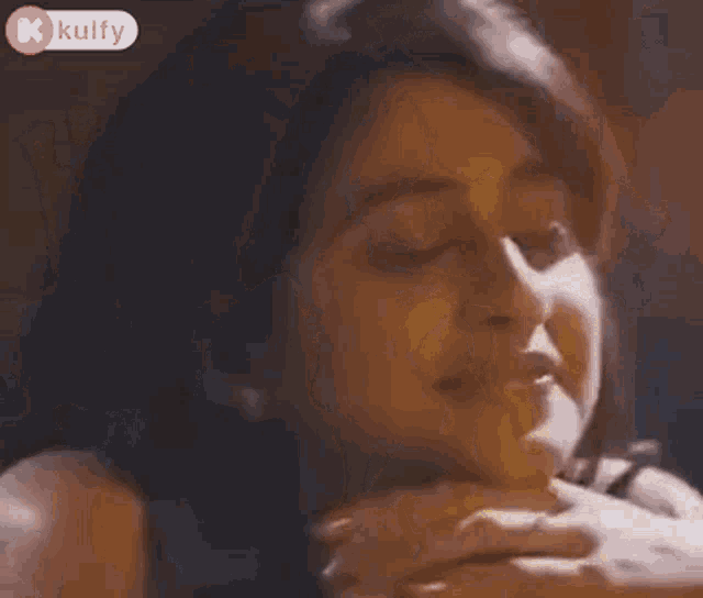 a woman is sitting in a dark room with her hands on her chin and a light behind her .