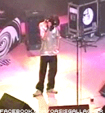 a man stands on a stage with a clock in the background and a facebook logo in the corner