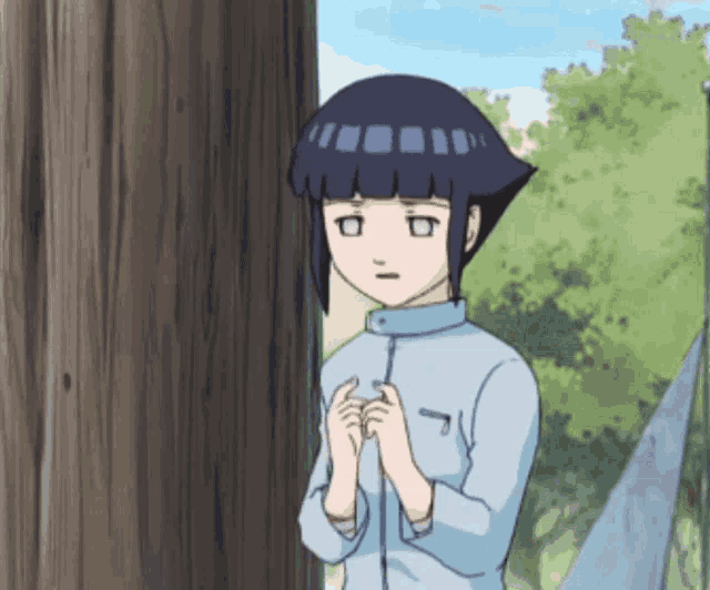 a girl in a blue shirt is standing next to a wooden pole