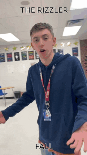 a young man in a blue hoodie is standing in a classroom with the words " the rizzler fall " written above him