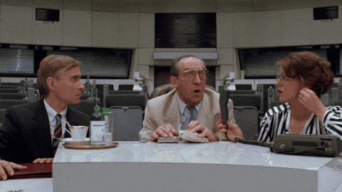 three people are sitting at a table and one of them has a bottle of water on the counter