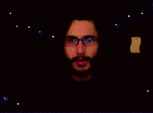 a blurry picture of a man with a beard and glasses in a dark room