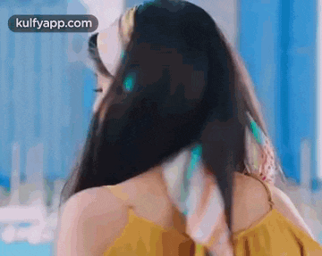 a woman in a yellow top is standing in front of a mirror .