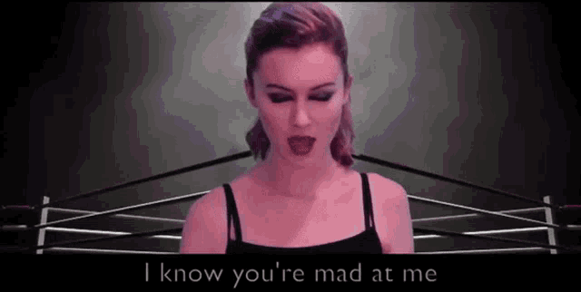 a woman is standing in a boxing ring with the words i know you 're mad at me below her