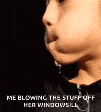a close up of a person blowing stuff out of their mouth .