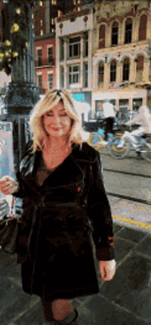 a woman in a black coat stands on a sidewalk in front of a sign that says ' toronto ' on it