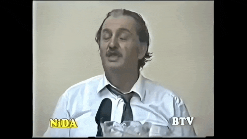 a man in a white shirt and tie is talking into a microphone with the words nida btv on the bottom
