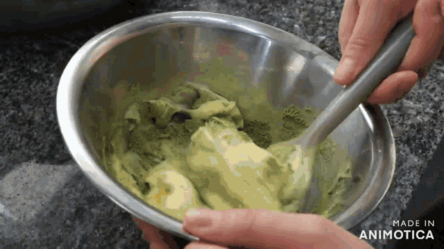 a person is mixing something in a metal bowl which says made in animatica