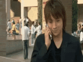 a man in a suit is talking on a cell phone in front of a crowd of people