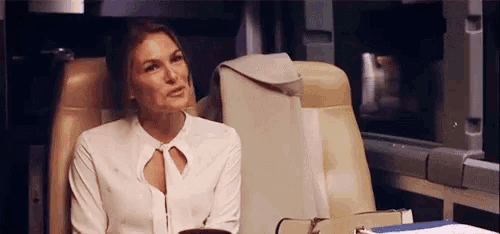 a woman in a white shirt is sitting in a chair on a train .