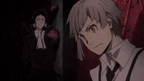 a man in a suit and tie stands next to another man in a black suit