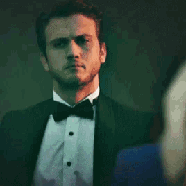 a man in a tuxedo adjusts his bow tie