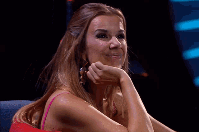 a woman in a pink dress is smiling with her hand on her face