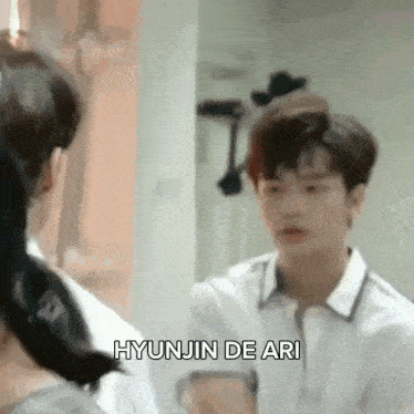 a young man in a white shirt is looking at himself in the mirror .