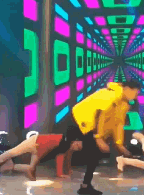 a man in a yellow shirt is doing a trick on a stage