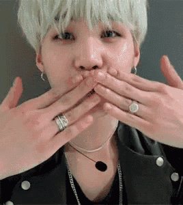 a man with a ring on his finger is blowing a kiss .
