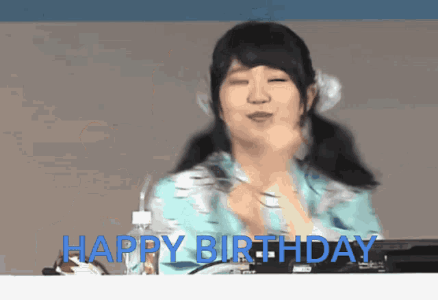 a girl is sitting at a table with her eyes closed and the words happy birthday written in blue