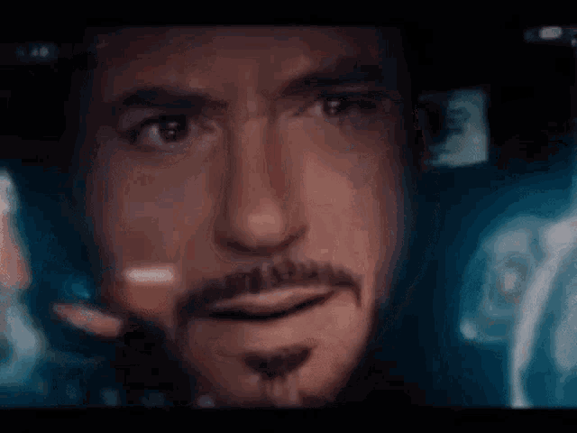a close up of a man 's face with a beard in front of a computer screen .