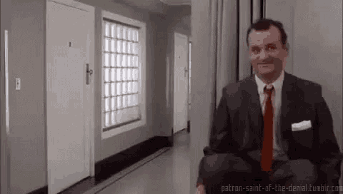 a man in a suit and red tie is sitting in a hallway .