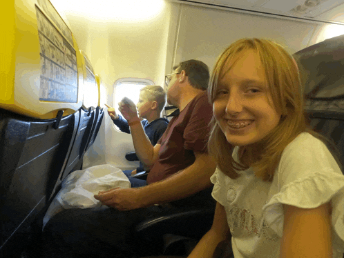 a girl sitting on a plane with a yellow sign on the wall that says ryanair
