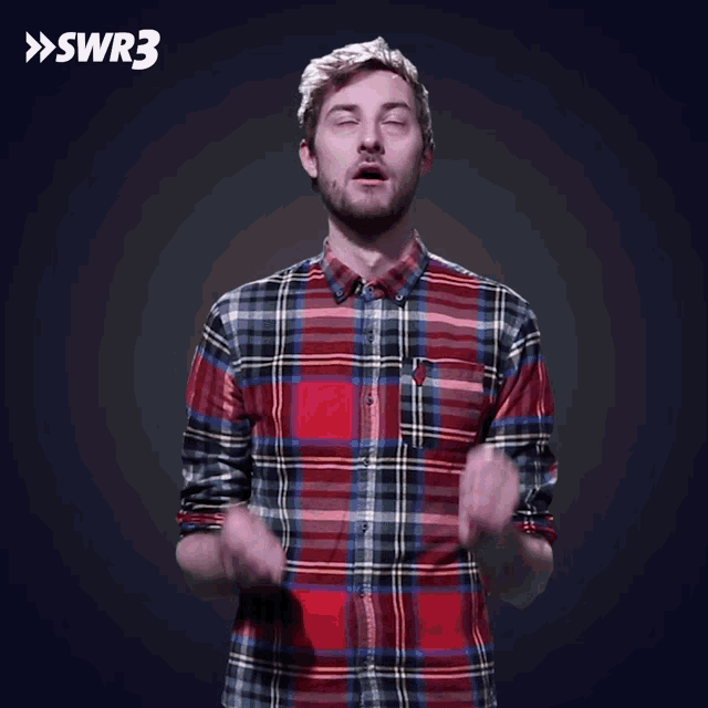 a man in a plaid shirt is making a funny face with swr3 in the background