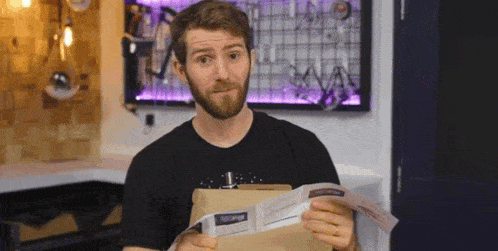 a man with a beard is holding an envelope and a book .