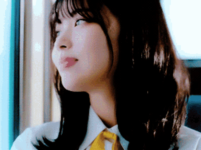 a woman wearing a white shirt and a yellow tie is looking out a window
