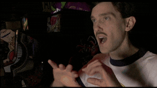 a man with a mustache is wearing a t-shirt that says " which is drop dead gorgeous "