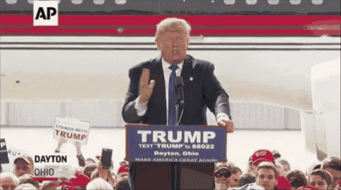 a man stands at a podium with a sign that says trump on it