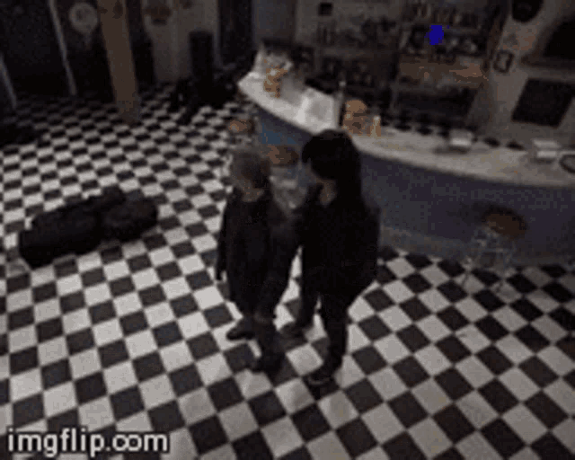 two people are standing in a room with a checkered floor