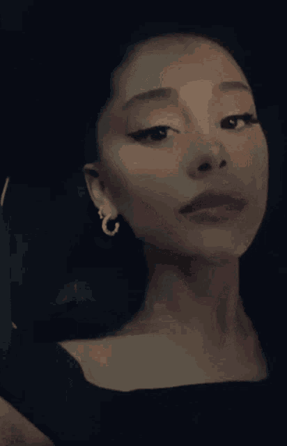 a close up of a woman wearing earrings and a black dress