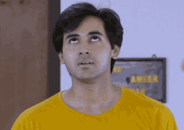 a man in a yellow shirt looks up at something in front of a sign that says ameer