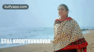 a woman in a sari is standing on a beach with the words still koduthunnavaa on the bottom .
