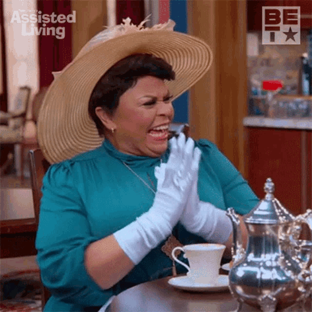 a woman wearing a hat and gloves is sitting at a table with a cup of coffee .