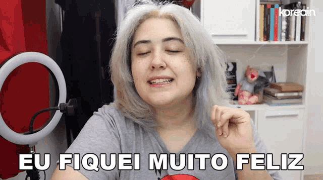 a woman says eu fiquei muito feliz in a room