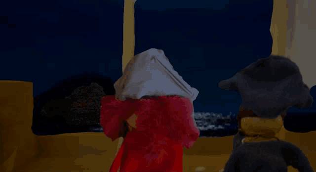 two stuffed animals are standing in front of a window at night