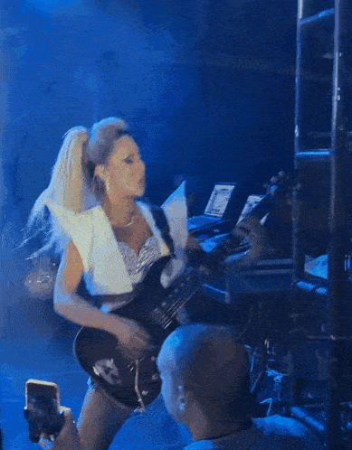 a woman is playing a guitar in front of a blue background