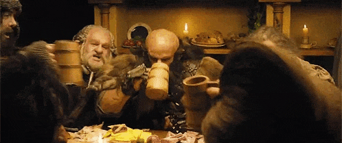 a group of dwarfs are sitting around a table drinking beer .