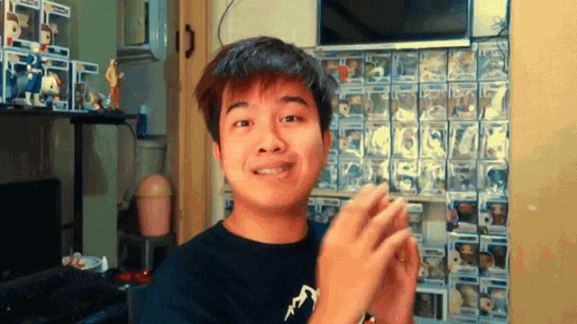 a young man is standing in front of a wall full of funko pop figures .