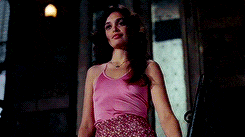 a woman in a pink tank top and pink skirt is standing in a doorway .