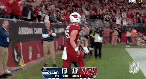 a football player in a red uniform is running on the field during a game against the seahawks .