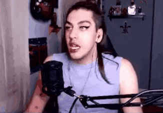 a man with long hair is talking into a microphone .