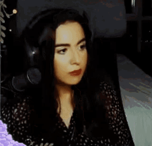 a woman is wearing headphones and making a funny face while sitting on a bed .