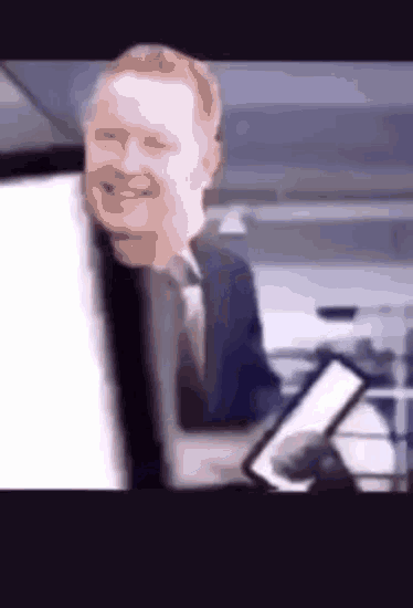 a man in a suit and tie is smiling while holding a piece of paper