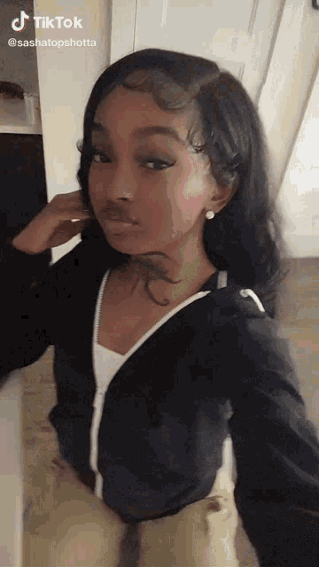 a girl with a tattoo on her neck is taking a selfie with a phone .