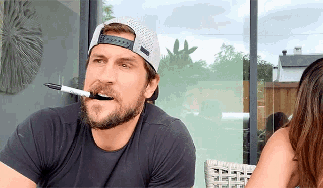 a man with a marker in his mouth and a hat on