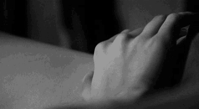 a black and white photo of a person 's hand on their arm