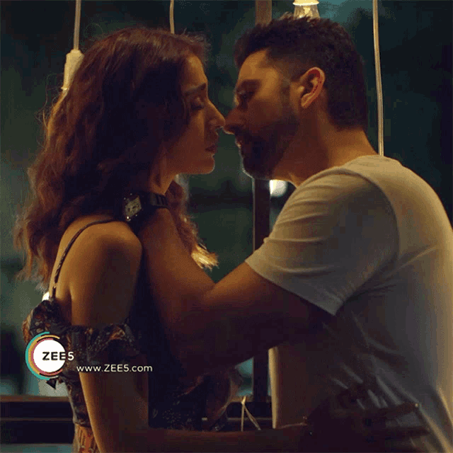 a man and a woman are kissing in front of a banner for zee5