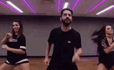a man and two women are dancing together in a gym .