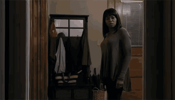 a woman is standing in a hallway with a basket in her hand